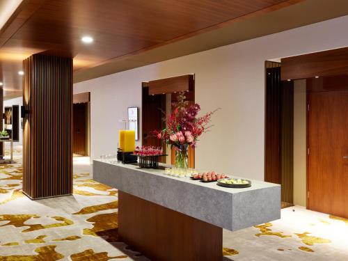 a lobby with a reception counter with flowers on it at PARKROYAL Melbourne Airport in Melbourne