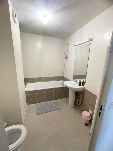 une salle de bain avec toilettes, baignoire et lavabo dans l'établissement Grand T2 spacieux très calme, à Bron