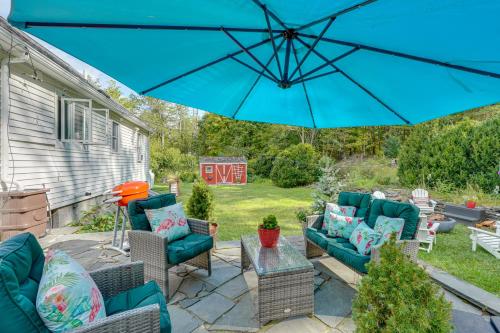 a patio with chairs and a blue umbrella at Saugerties Farmhouse Sauna and Countryside Views in Saugerties