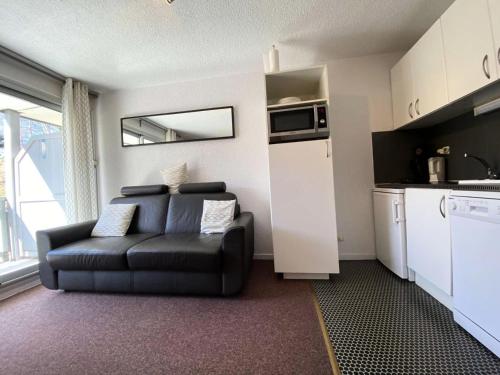 un salon avec un canapé noir et une cuisine dans l'établissement Résidence Kandahar - Agréable studio au centre de la station MAE-5691, à Vénosc