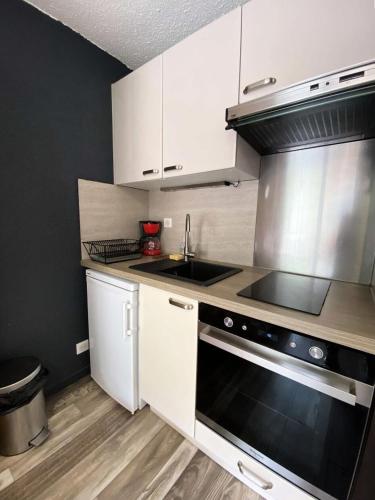 une cuisine avec un évier et une cuisinière four supérieur dans l'établissement Résidence Kandahar - Agréable appartement esprit montagne, en centre station MAE-5701, à Vénosc