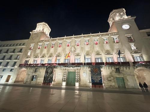 un grand bâtiment avec une tour d'horloge la nuit dans l'établissement My Flat in Rambla, à Alicante