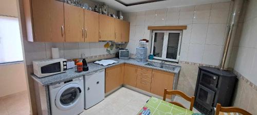 a small kitchen with a washing machine and a microwave at Casa VazPeralta in Castanheira de Pêra