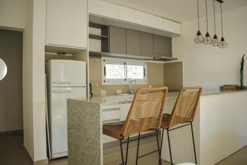 a kitchen with two chairs and a white refrigerator at Conana Apartment in Villa Mercedes