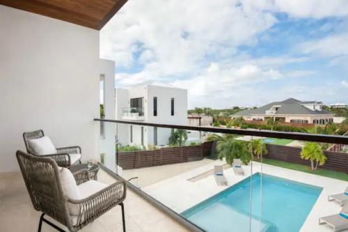 a balcony with a view of a swimming pool and chairs at Villas private pool Long Bay Hills, Turks and Caicos Islands in Long Bay Hills