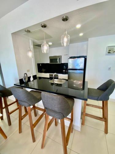 a dining room with a black table and chairs at LasOlasTower JuanDolio-2Br-3Bds-7Px-WiFi-SeaView in Juan Dolio