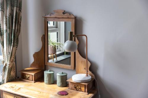 a mirror on top of a wooden table with a lamp at CloudZen in Kent