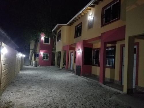 an empty street at night with pink and yellow buildings at Arbolada Talas del Tuyu in San Clemente del Tuyú
