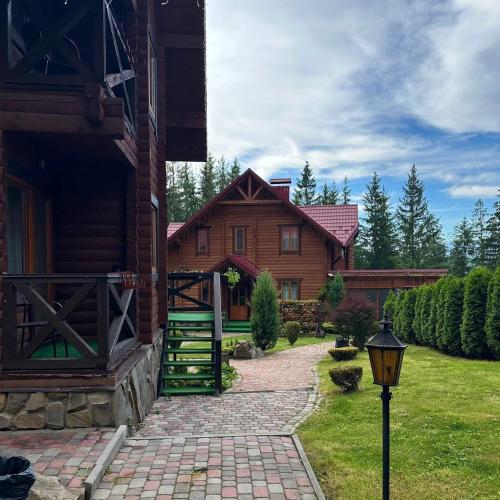 a wooden house with a gate and a walkway to it at GORGANY resort & SPA in Yablunytsya