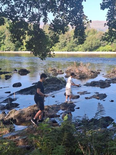 two people fishing on the rocks in a river at Twin Deer Lodge in Glenfinnan