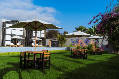 a group of tables and chairs with umbrellas next to a pool at Awqa Loft & Camp in Trujillo