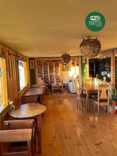 a living room with wooden floors and tables and chairs at Travesia Hotel & Tea in Ancud