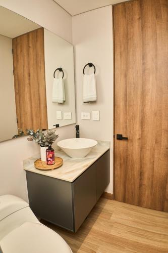 a bathroom with a white sink and a wooden door at HYPE STATES Cali in El Peñón