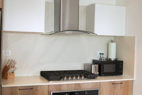 a kitchen with a stove and a microwave at Luxury Retreat Condo 3BR Pool & Spa Azzure-Cap Cana in Punta Cana