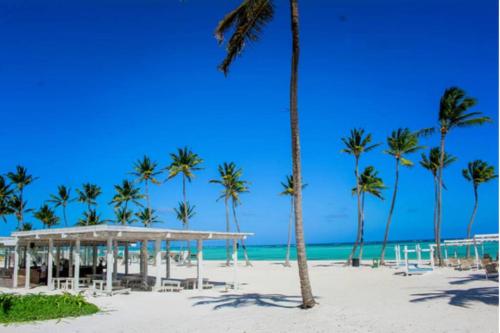 a beach with palm trees and a pavilion on the beach at Luxury Retreat Condo 3BR Pool & Spa Azzure-Cap Cana in Punta Cana
