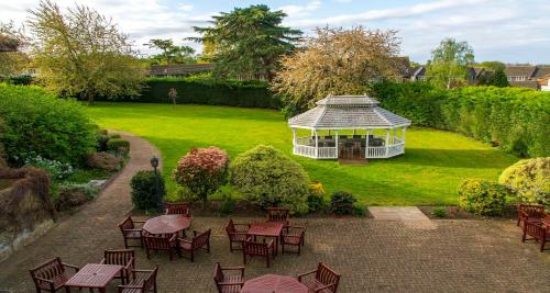 a garden with a gazebo and tables and chairs at London Chigwell Prince Regent Hotel, BW Signature Collection in London