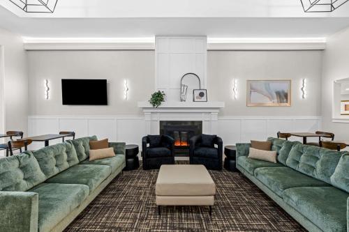 a living room with green couches and a fireplace at Best Western Plus Puyallup Hotel in Puyallup
