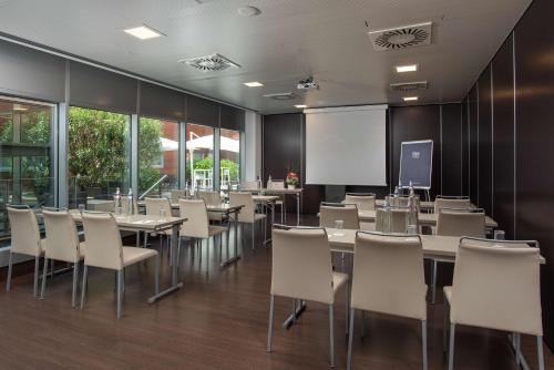 a conference room with tables and chairs and a whiteboard at NH Orio Al Serio in Orio al Serio