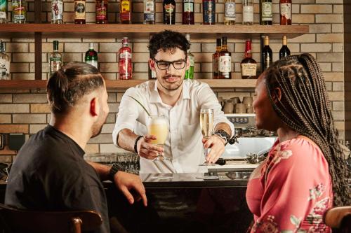 a bartender making drinks at a bar with two people at Radisson Resort Ras Al Khaimah Marjan Island in Ras al Khaimah