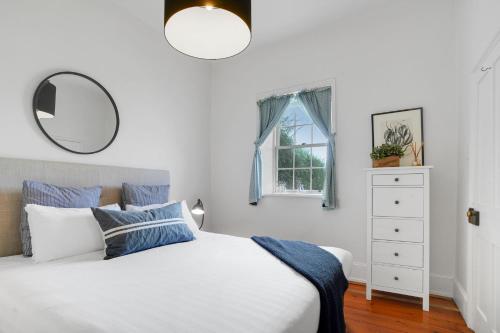 sypialnia z białym łóżkiem i lustrem w obiekcie Prues Cottage w mieście Port Fairy