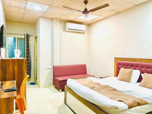 a bedroom with two beds and a red couch at JAGTARA RESIDENCY in Indore