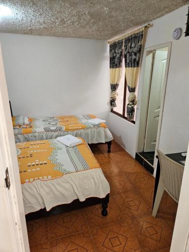 a room with two beds and a mirror at Hostal Cerro Azul in Puerto Villamil
