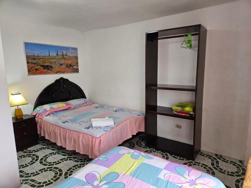 a bedroom with two beds and a book shelf at Hostal Cerro Azul in Puerto Villamil