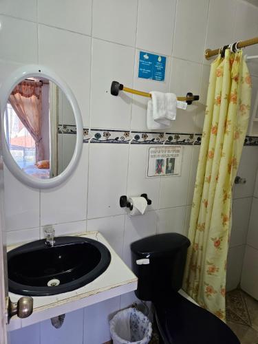 a bathroom with a sink and a mirror and a toilet at Hostal Cerro Azul in Puerto Villamil