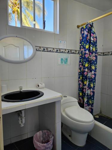a bathroom with a toilet and a sink and a mirror at Hostal Cerro Azul in Puerto Villamil