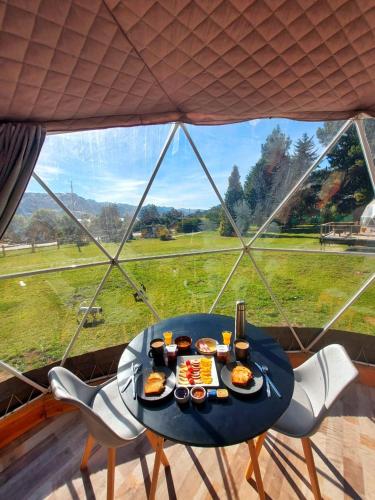 特拉福镇Glamping Vulcanche的一张桌子,上面有食物,放在大窗户前