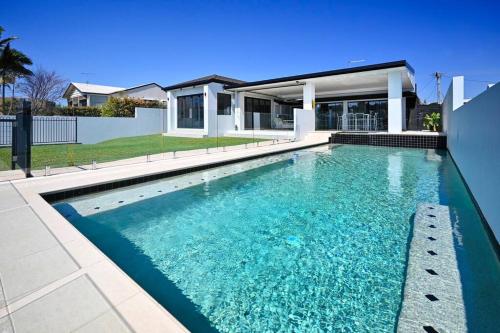 a swimming pool in front of a house at Mooloolaba Waterfront Luxury in Mooloolaba