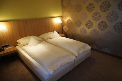 a large white bed in a room with two lamps at Hotel Schepers in Gronau