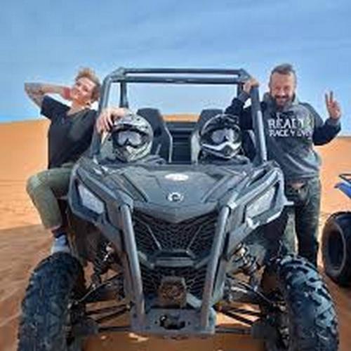 a man and a woman sitting in a atv in the desert at Aaladdin luxury camp in Merzouga