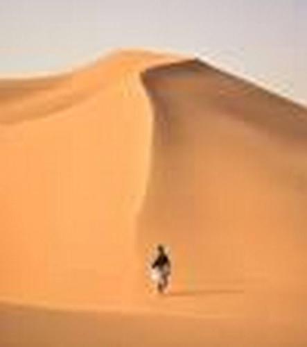 a person standing in the sand in the desert at Aaladdin luxury camp in Merzouga