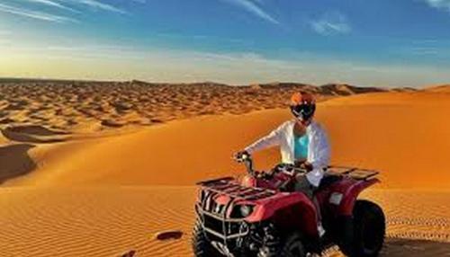 a person riding a quad bike in the desert at Aaladdin luxury camp in Merzouga
