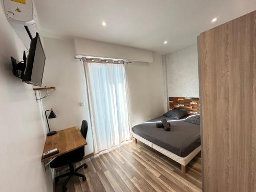 une chambre avec un lit, un bureau et une télévision dans l'établissement Appartement Spacieux - 4 chambres confortables, à Nice