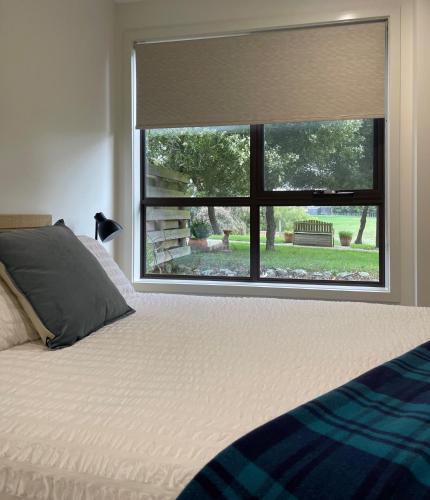 a bedroom with a bed and a window with a blind at Bundaleera Vineyard and Farm Stay in Relbia