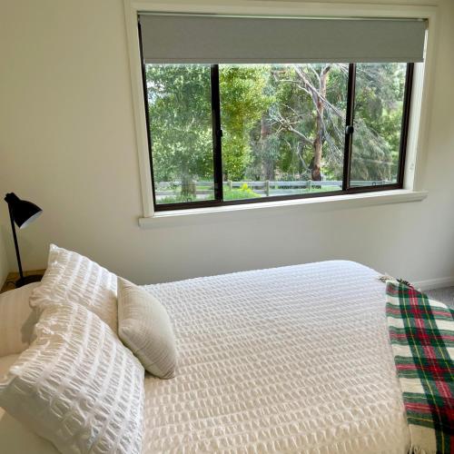 a bedroom with a bed with a large window at Bundaleera Vineyard and Farm Stay in Relbia