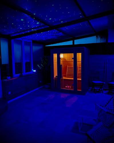 Cette chambre est dotée de lumières bleues, d'une table et de chaises. dans l'établissement Bohème Spa&Sauna Orléans, à Saint-Jean-de-Braye