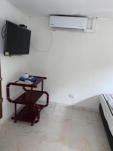 Una habitación con una mesa y un televisor en una pared. en CASA HOTEL TOSCANINI (T), en Cali