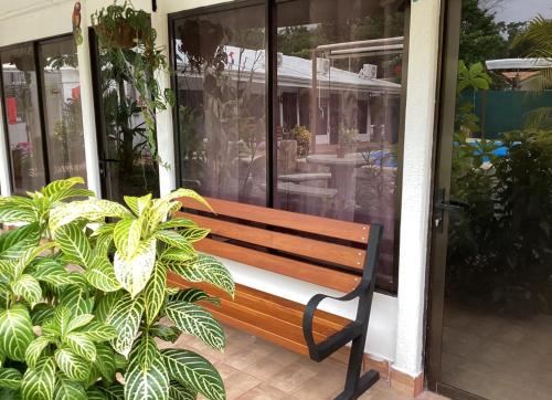 a wooden bench sitting in front of a house at Habitaciones Kolibri in Quepos