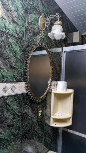 a bathroom with a mirror on a wall with a shelf at Canoas Hotel Castel in Canoas