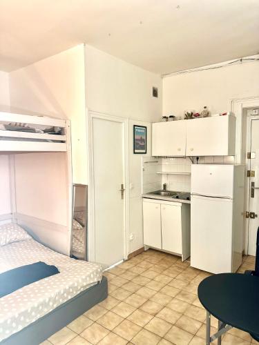 Cet appartement comprend une chambre avec un lit et une cuisine avec des placards blancs. dans l'établissement Appartement confort Paris 75009, à Paris