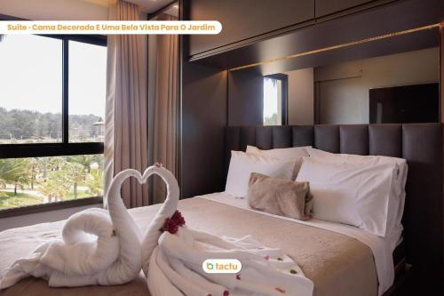 deux cygnes en blanc sont assis sur un lit dans l'établissement Appartement Moderne au VG Sun Cumbuco par Tactu, à Paracumbuca