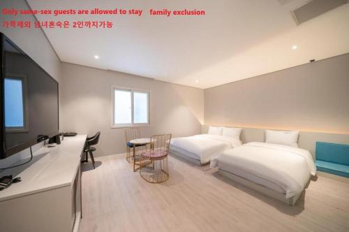 a bedroom with two beds and a tv and a desk at Hotel LeeSunDeok in Busan