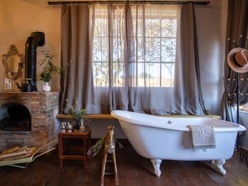 a large bath tub in a room with a window at Chalé Vilarejo - Vila Monte Cunha in Cunha