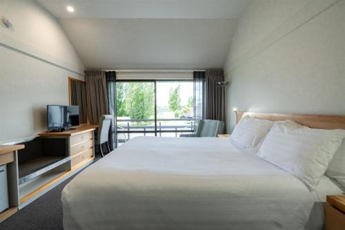 a hotel room with a bed and a television at Edgewater Hotel in Wanaka