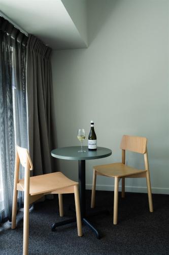 a table and two chairs and a glass of wine at Edgewater Hotel in Wanaka