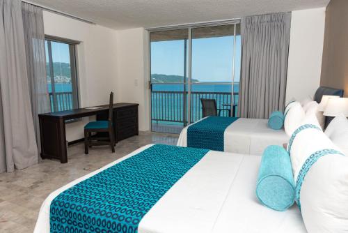 アカプルコにあるRitz Acapulco All Inclusiveのベッド2台、デスク、バルコニーが備わる客室です。