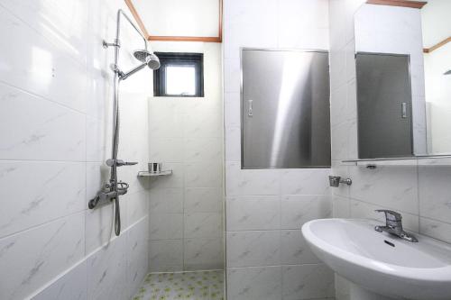 a white bathroom with a sink and a shower at Sokcho Ritz Hotel in Sokcho